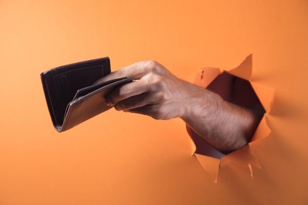 Hand holds wallet on orange background