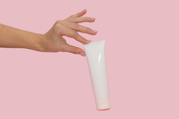 Hand holds a white container with cosmetic cream For body care