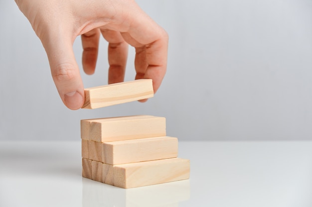 Hand holds wooden blocks on top of ladder