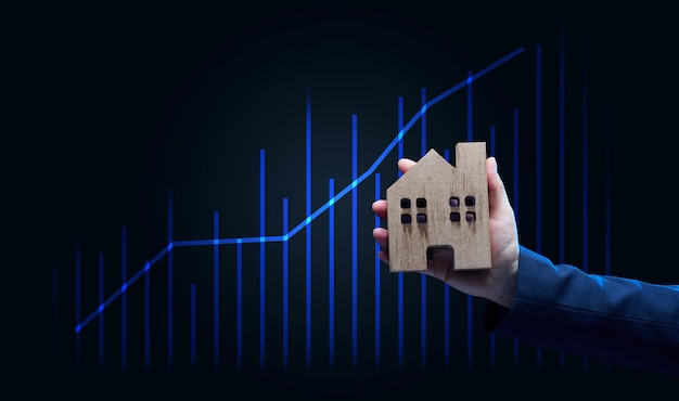 Hand holds a wooden model of a house on a dark background Real estate sale