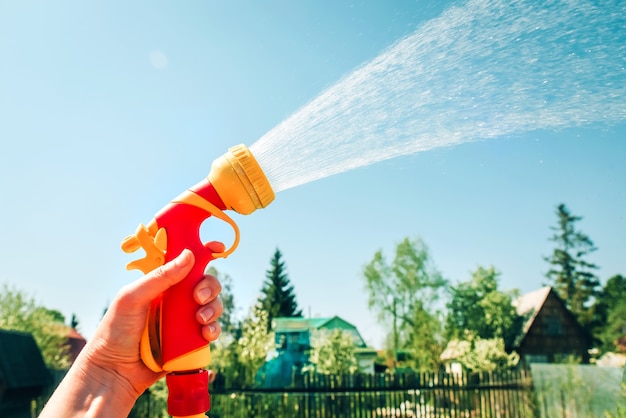 Hand holds a yellow hose with a nozzle