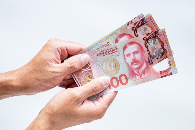 Hand holing Nieuw-Zeeland 100 dollar biljetten op witte achtergrond