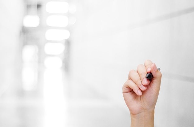 Hand holing pen over blurred office background