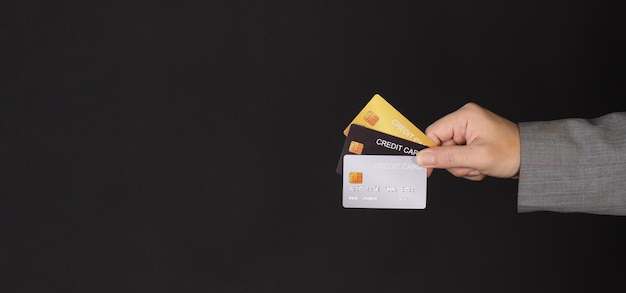 Hand houdt drie creditcards geïsoleerd op zwarte achtergrond