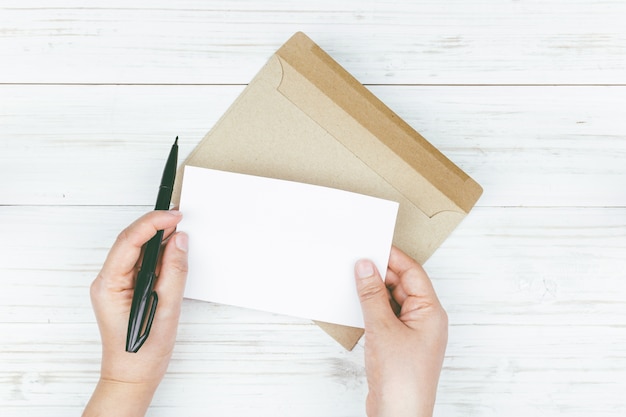 Hand houdt een envelop en papier op de houten achtergrond