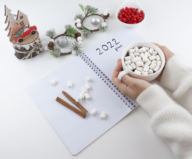 hand houdt een kopje koffie op tafel is een notitieboekje met het opschrift 2021