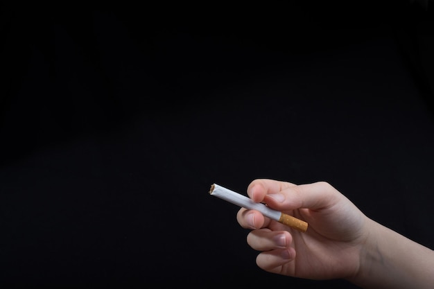 Hand houdt een sigaret op zwarte achtergrond