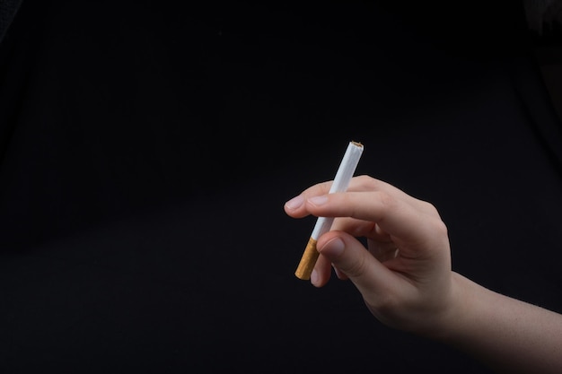 Hand houdt een sigaret op zwarte achtergrond