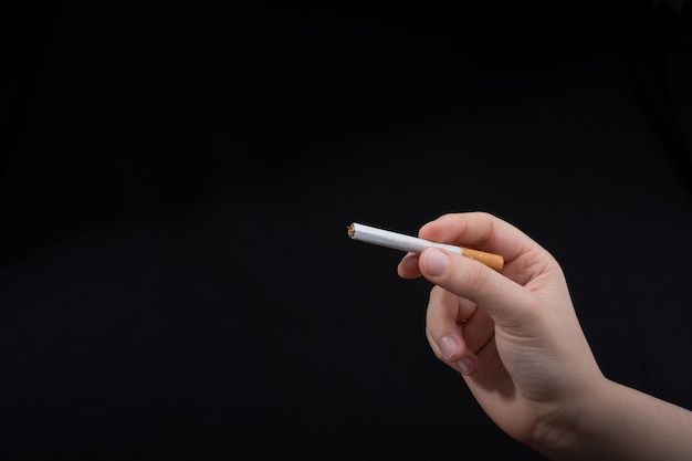 Hand houdt een sigaret vast op een zwarte achtergrond