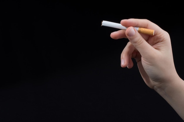 Hand houdt een sigaret vast op een zwarte achtergrond