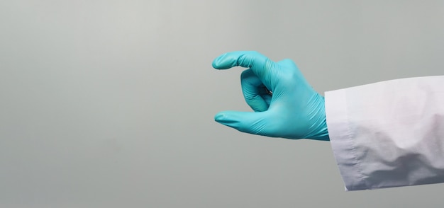 Hand houdt gebaar vast en draagt doktersjurk en blauwe medische handschoen op een grijze achtergrond.