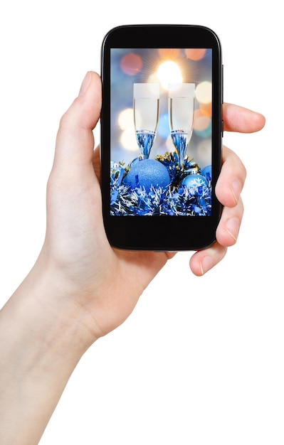 Foto hand houdt mobiele telefoon vast met kerststilleven