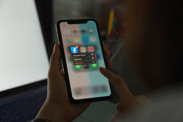 Hand houdt telefoon vast en verwijdert Facebook-scherm