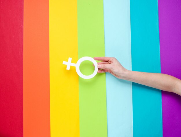 Foto hand houdt vrouwelijk geslacht symbool op regenboog achtergrond