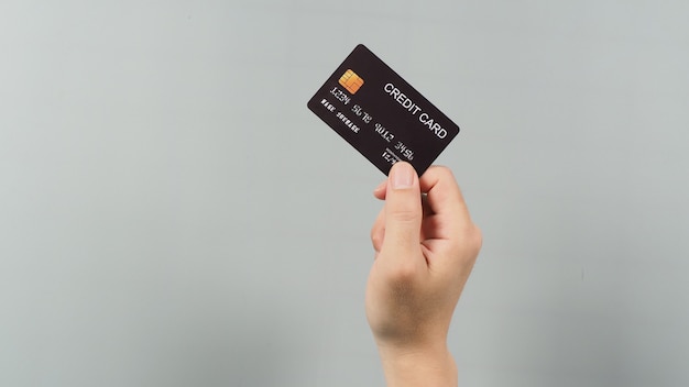 Hand houdt zwarte creditcard geïsoleerd op een grijze achtergrond.