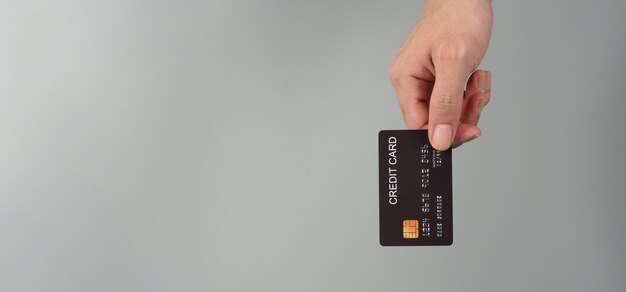 Hand houdt zwarte creditcard geïsoleerd op een grijze achtergrond.