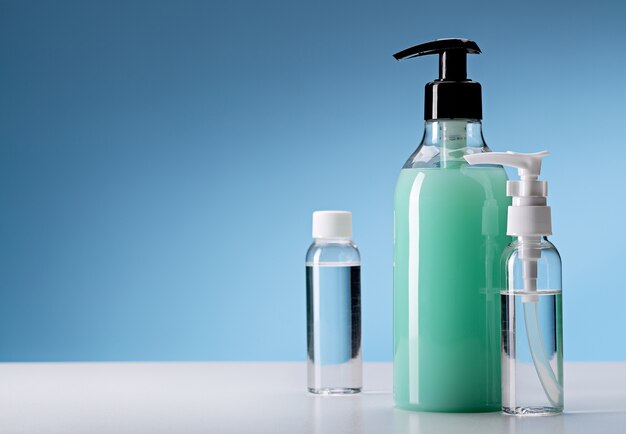 Hand hygiene disinfectants. Spray bottles on blue space, copy space.