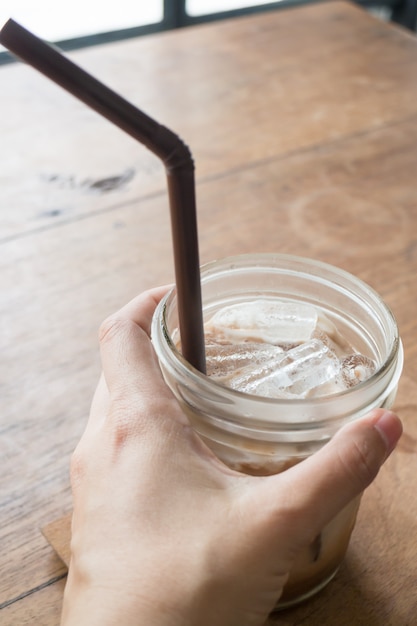 Hand on iced glass of latte coffee