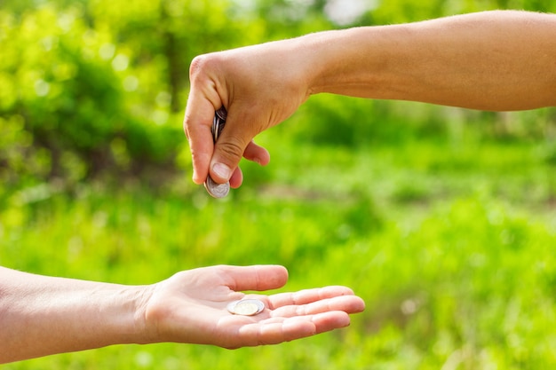 Hand in hand geeft munten op groene achtergrond, Financiën concept en leningen.