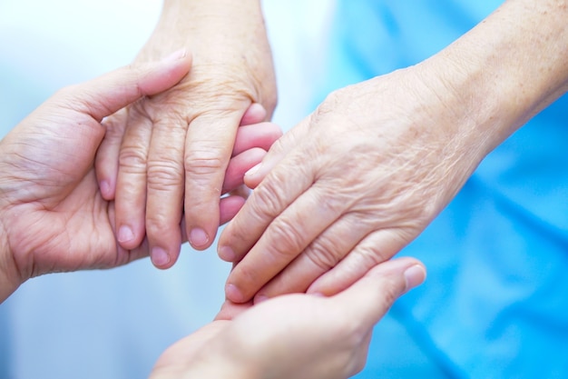 Hand in hand met Aziatische senior patiënt met liefde