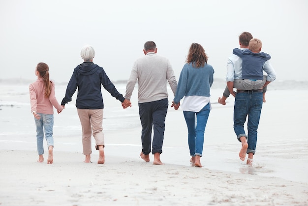 Hand in hand wandelen en grote familie op het strand om te oefenen terwijl ze op zomervakantie zijn Grootouders, ouders en kinderen op buitenwandeling in de natuur door de oceaan tijdens vakantieavontuur of reis