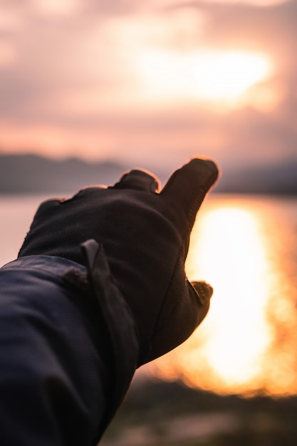 Hand in handschoen wijzend naar de zon