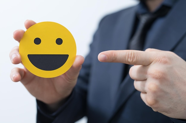 Hand in pak die een smiley emoji vasthoudt en ernaar wijst