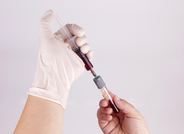 Photo hand injecting blood sample into test tube
