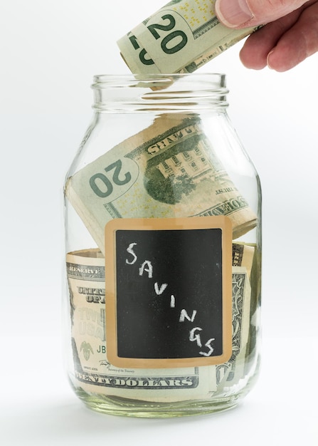 Hand inserting money into saving jar or bank