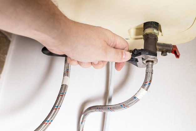 Photo hand installs valve by adjustable wrench on boiler