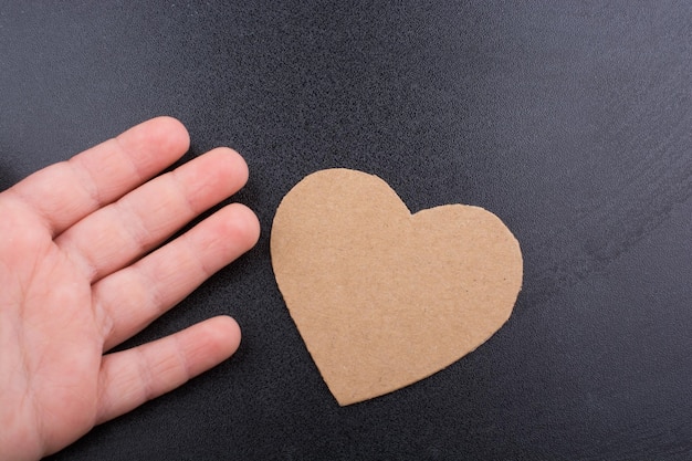 Hand is beside a heart shaped object on black