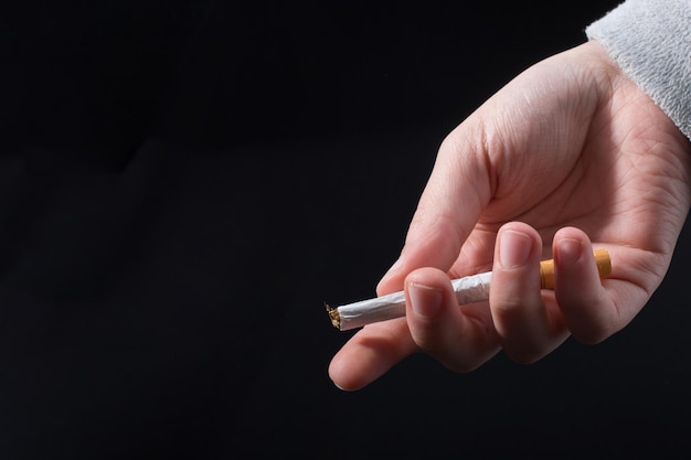 Foto la mano sta distribuendo la sigaretta su sfondo nero