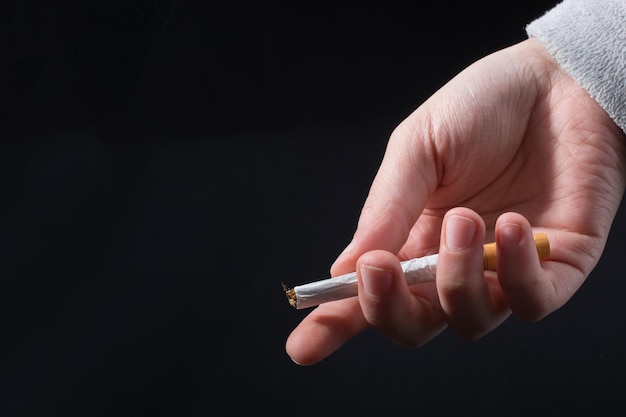 Hand is giving out cigarette on a black background