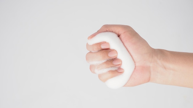 La mano è tenere il sapone per le mani schiumogeno per il lavaggio su sfondo bianco.