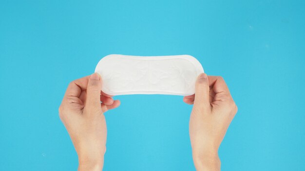 Hand is hold Hygienic daily panty liner isoalted on blue background.