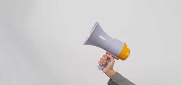 Hand is hold megaphone and wear grey suit on white background.