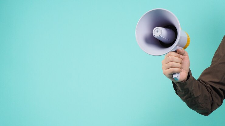 Photo hand is hold megaphone and wear navy color shirt on green or mint or tiffany blue background.