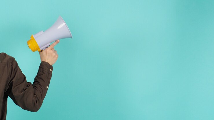 Photo hand is hold megaphone and wear navy color shirt on green or mint or tiffany blue background.