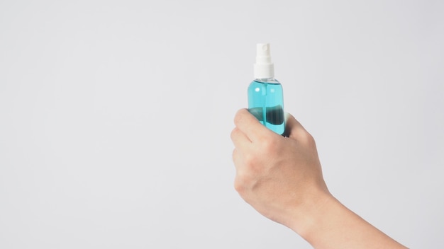 Hand is holding alcohol spray on white background.