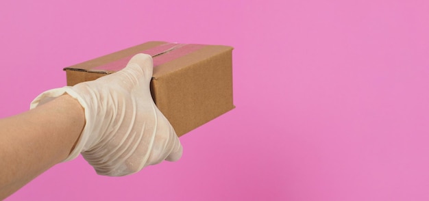 The hand is holding a brown box isolated on pink background