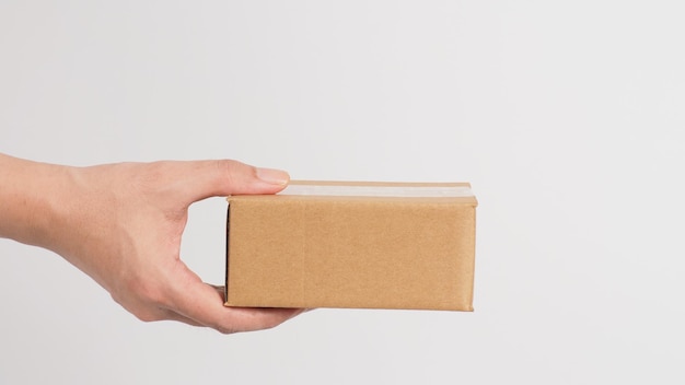 Hand is holding brown box isolated on white background.