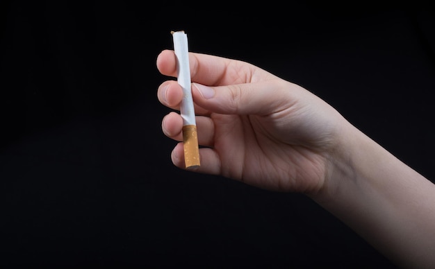 Photo hand is holding a cigarette on black background