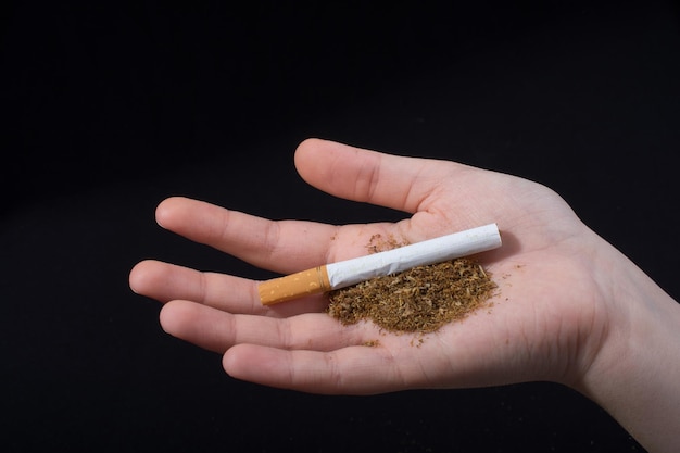 Hand is holding a cigarette on black background