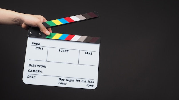 Hand is holding clapper board or movie slate.It is used in video production and film industry on black background.