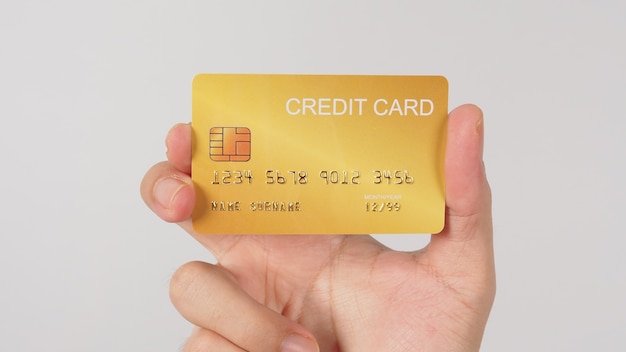 Рука держит золотую кредитную карту, изолированную на белом фоне.