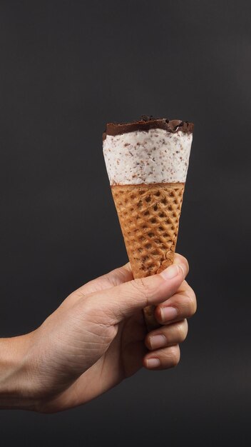 Hand is holding ice cream cone with black background