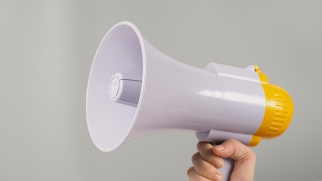 A hand is holding megaphone on grey background