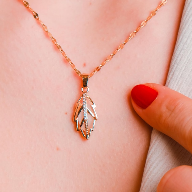 A hand is holding a necklace with a bird on it.