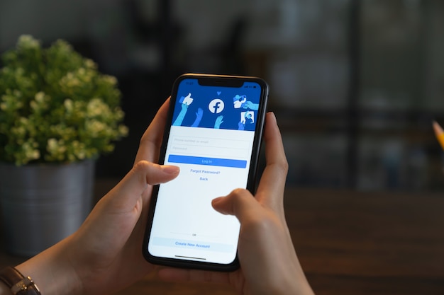 Foto la mano tiene il telefono e lo schermo di facebook sullo smartphone