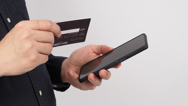 Hand is holding smart phone and black credit card on white background. OLYMPUS DIGITAL CAMERA